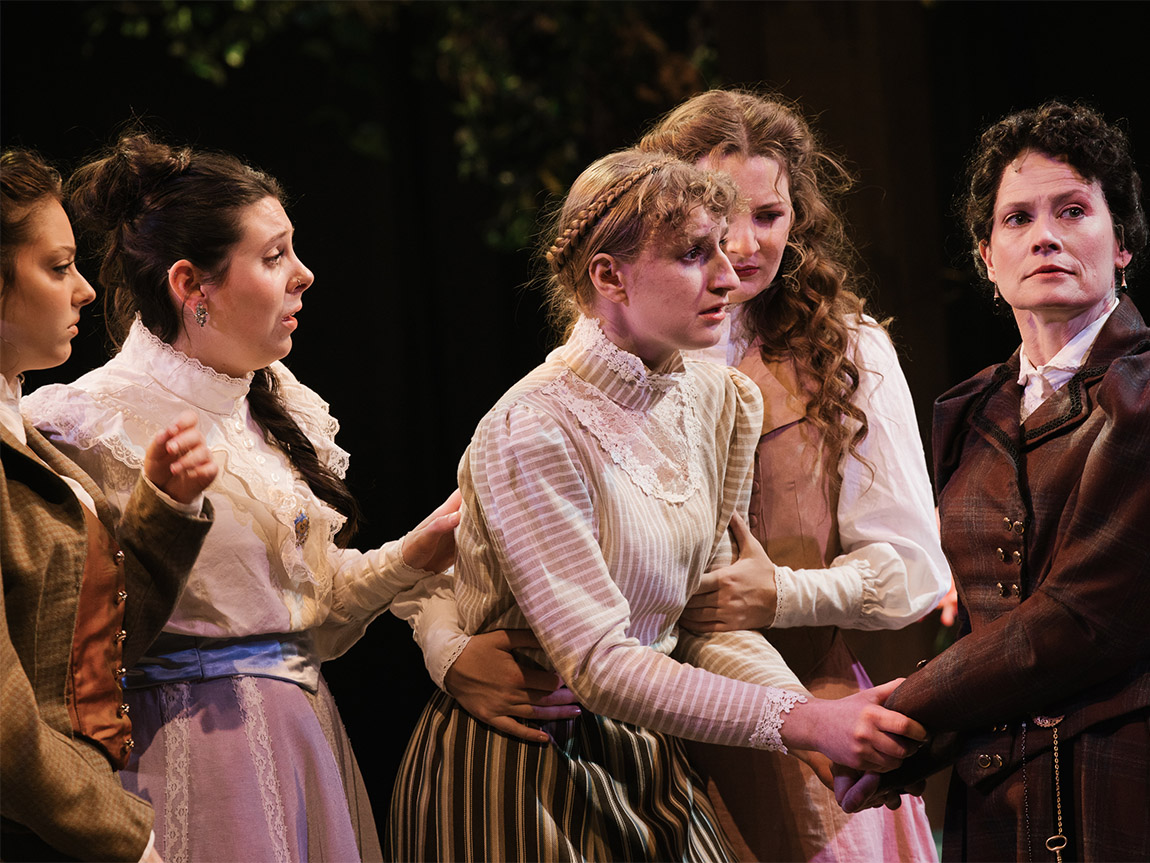 Photo of five women on stage dressed in Victorian-era clothes.